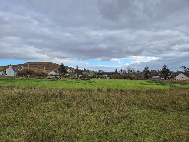 Open croft land at Kilmuir near Dunvegan on the Isle of Skye, showing flat grassland with distant views towards MacLeod’s Tables under a wide Highland sky.