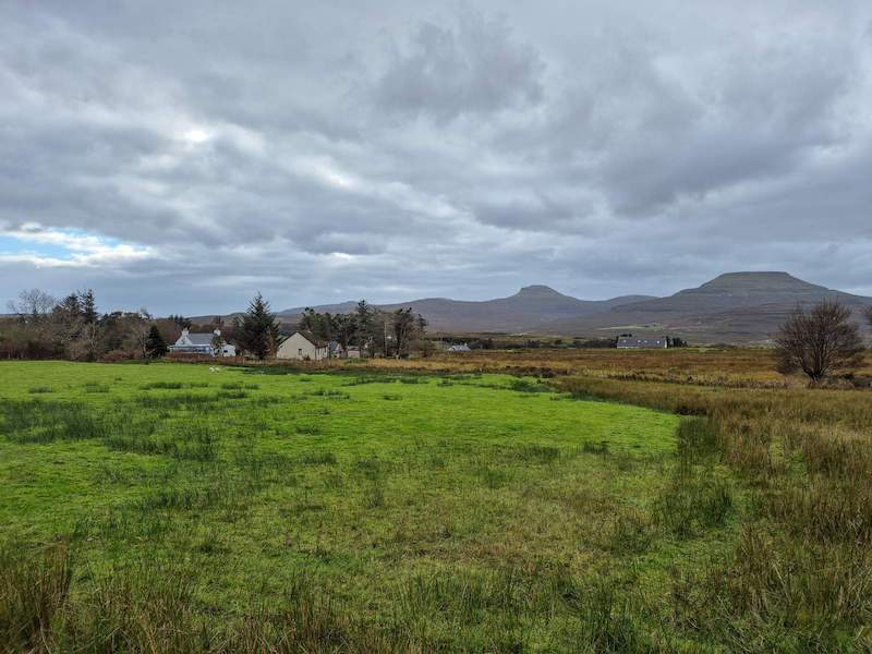 Open croft land at Kilmuir near Dunvegan on the Isle of Skye, showing flat grassland with distant views towards MacLeod’s Tables under a wide Highland sky.
